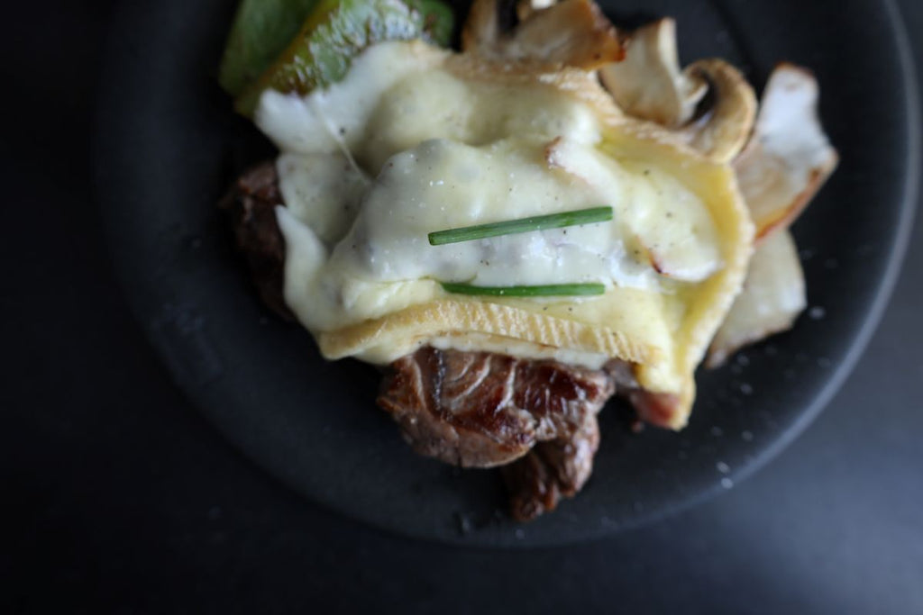 raclette cheese on steak and veggies