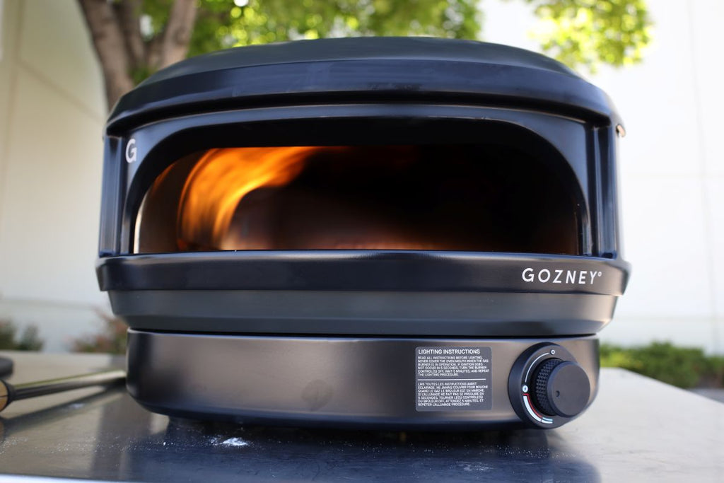 Gozney pizza oven cooking a homemade pizza outdoors on a backyard patio