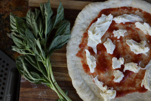Beginner making homemade pizza in an outdoor pizza oven during backyard pizza night