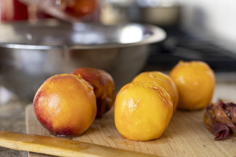 Preparing and peeling peaches in the kitchen for atmospheric steam canning.