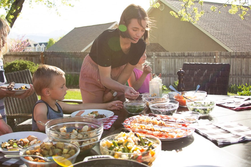 family gathering around a backyard picnic table for pioneer day