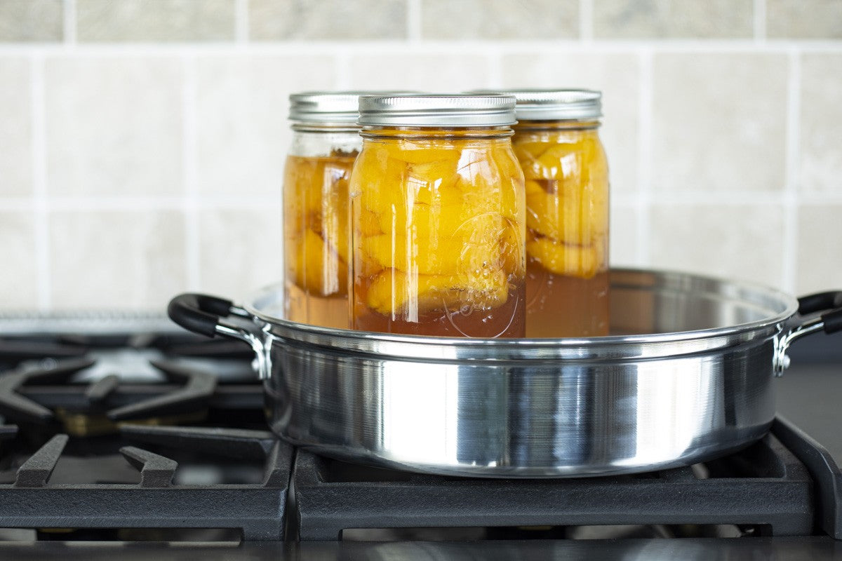Beginner-friendly steam canning setup with jars of homemade jam and a steam canner on a kitchen counter