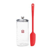 Clear container with lines to measure sourdough starter growth with silver lid and red spatula on a white background