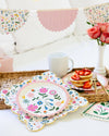Floral plates and a mug on a table with a decorative background