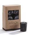 Black unscented candle in front of a cardboard box packaging with 'MAISON' branding.