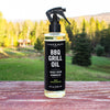 Bottle of Caron & Doucet BBQ Grill Oil on a wooden surface with a scenic background