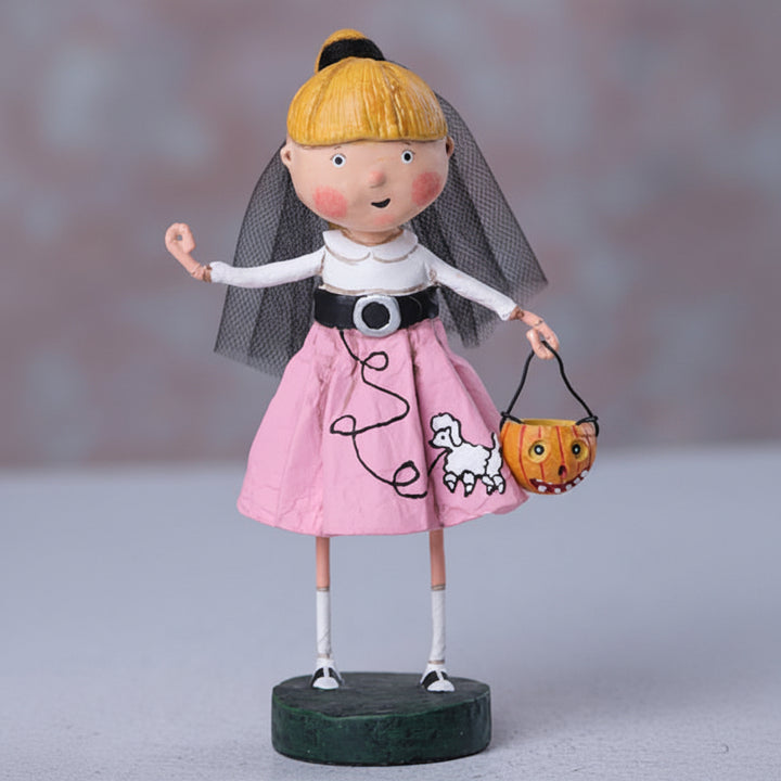 Decorative figurine of a girl in a pink dress with a pumpkin basket on a gray background