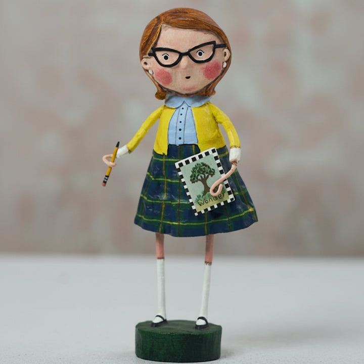 Figurine of a girl in a school uniform holding a book and pencil on a plain background