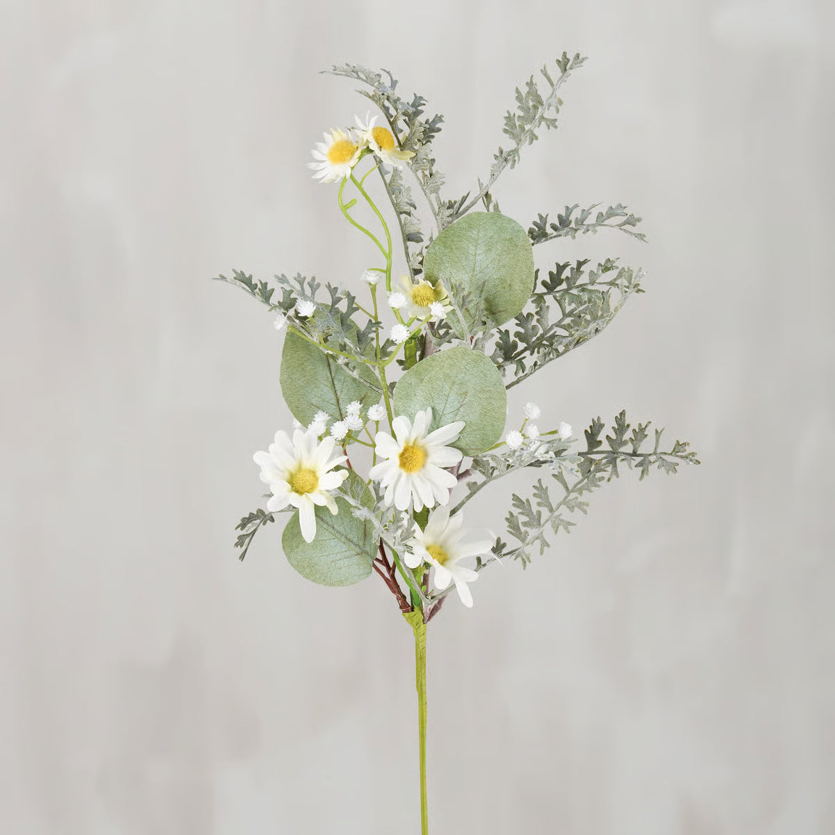 Artificial flower arrangement with daisies and greenery on a light gray background