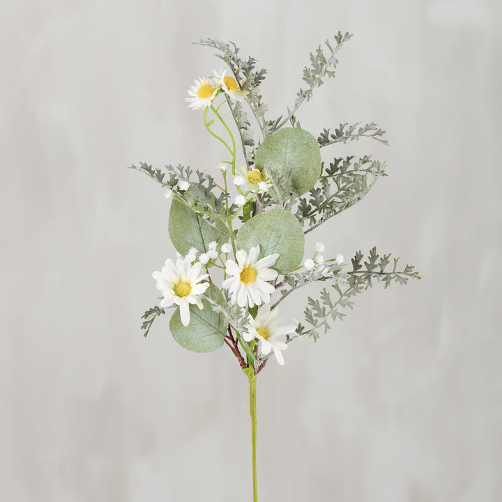 Artificial flower arrangement with daisies and greenery on a light gray background
