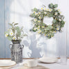 Decorative wreath and potted plant on a table with a light blue wooden background