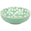 Green bowl with white floral pattern on a white background