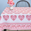 Tablecloth with pink heart patterns on a table against a blue wall.