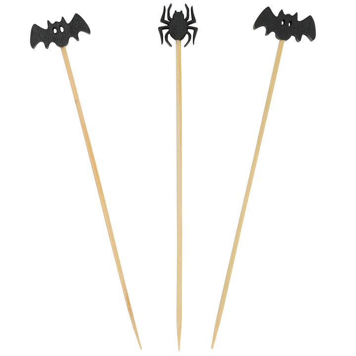 Three Halloween-themed cocktail picks on wooden sticks, featuring black bat and spider cutouts at the top, shown against a plain white background.
