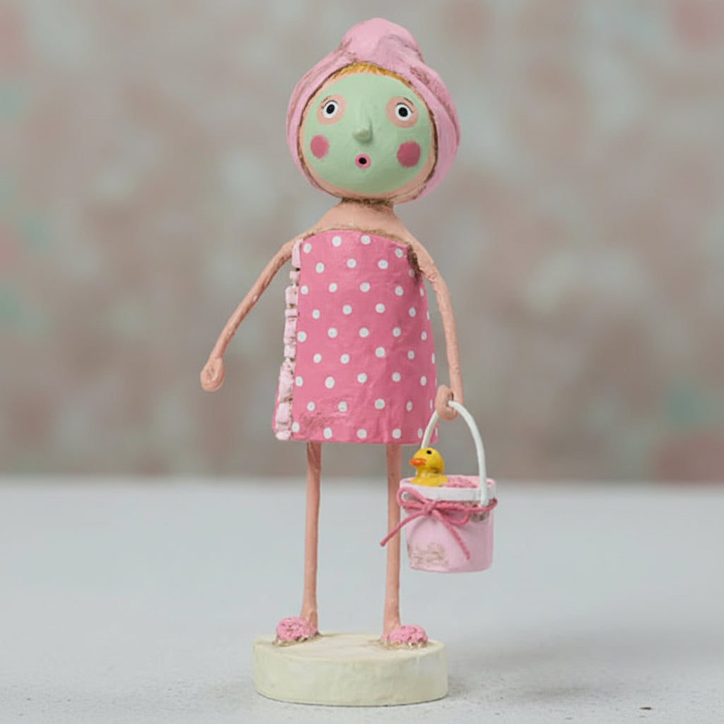 Figurine of a girl in a polka dot towel with a pink towel on her head, holding a small bucket with a duck toy.