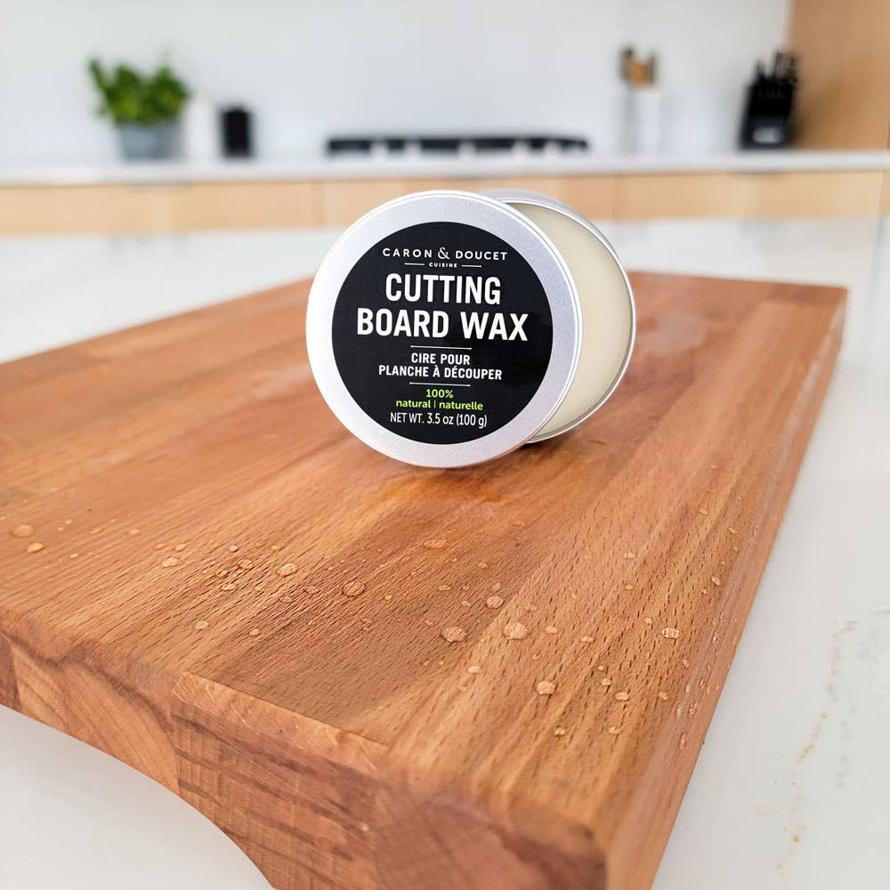 Cutting board wax container on a wooden cutting board with a kitchen background