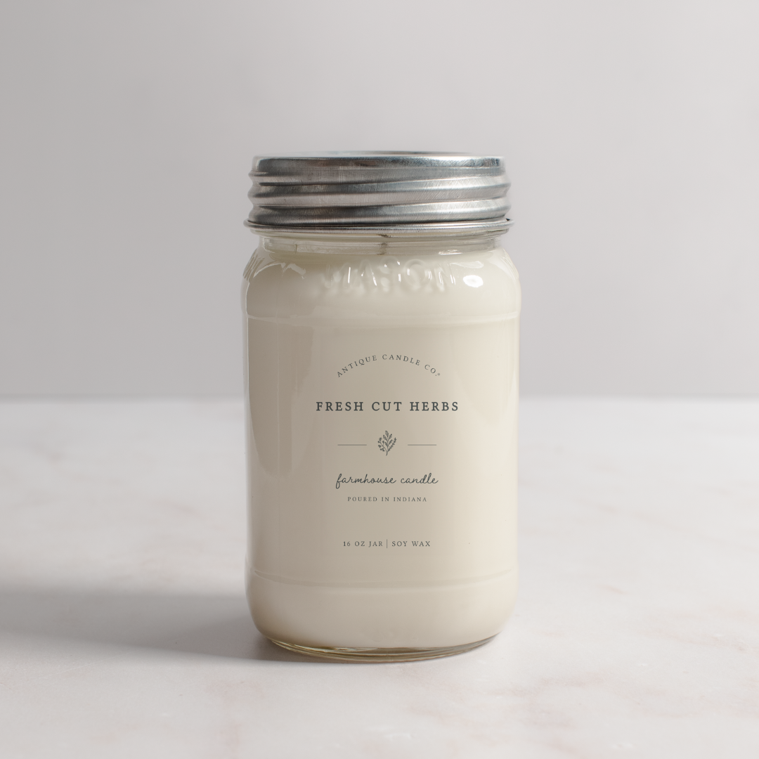 Jar candle labeled 'Fresh Cut Herbs' on a light background