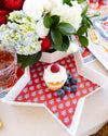 Cupcake with berries on a decorative tablecloth with flowers in the background
