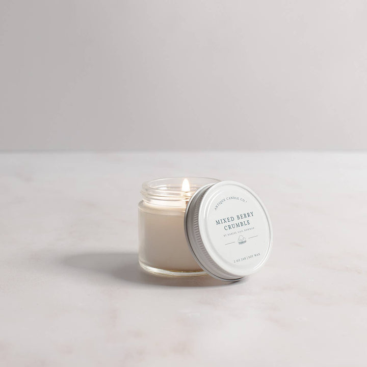 Candle in a glass jar with a white lid on a light gray background