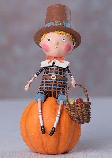 Decorative figurine of a boy in pilgrim attire sitting on a pumpkin with a basket.