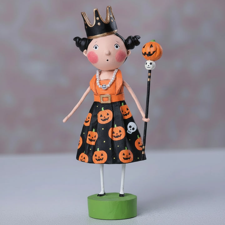 Halloween-themed figurine with a black dress featuring pumpkins and skulls, an orange top, and a crown.
