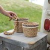 Woven baskets with decorative bands on a vintage suitcase outdoors