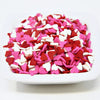 White bowl filled with red, pink, and white heart-shaped sprinkles on a white background