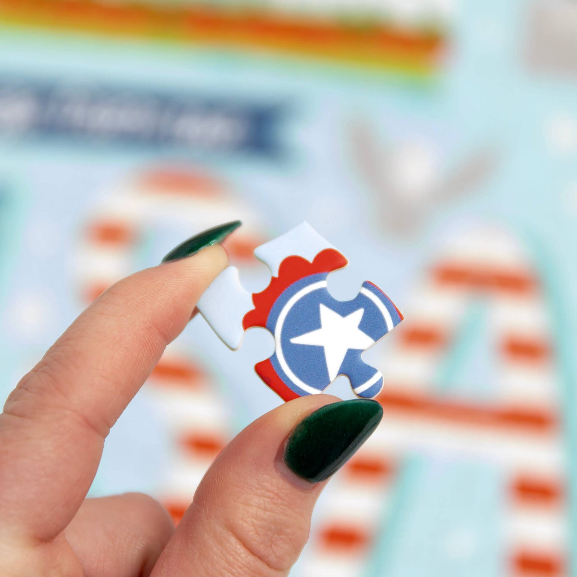 Hand holding a small puzzle piece with a star design against a blurred background