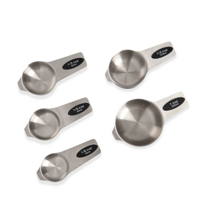 Set of five stainless steel measuring cups with black labels on a white background