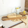 Wooden cutting board with bread and a pitcher of lemon water on a kitchen counter.