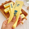 Hand squishing a block of butter toy with other butter blocks in the background.