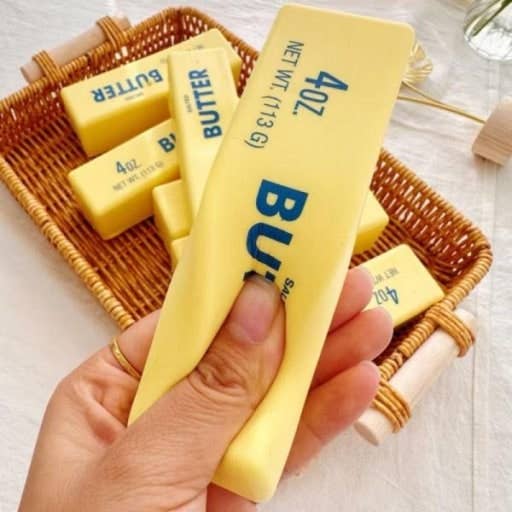 Hand squishing a block of butter toy with other butter blocks in the background.