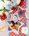 Star-shaped trays with snacks on a decorative tablecloth with flowers and berries.