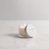 Candle in a glass jar with a white lid on a light gray background