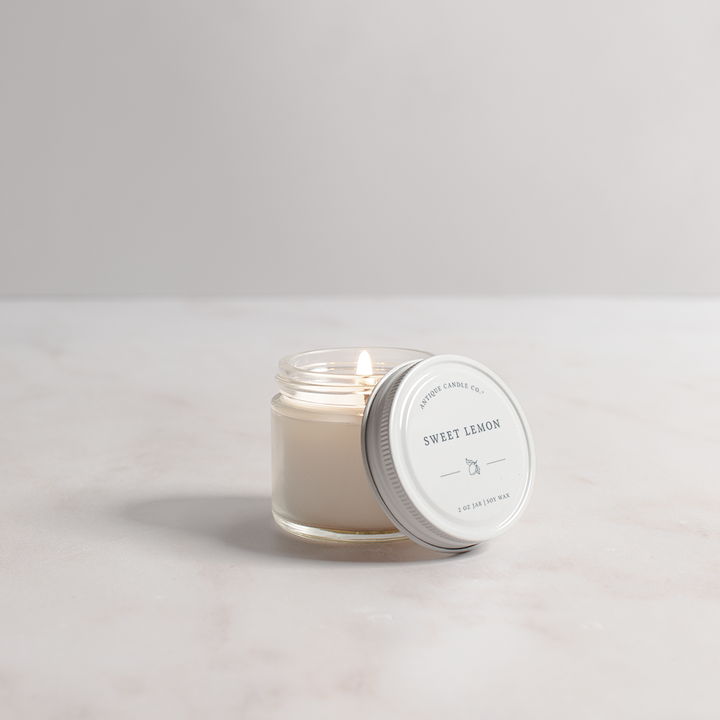 Candle in a glass jar with a white lid on a light gray background