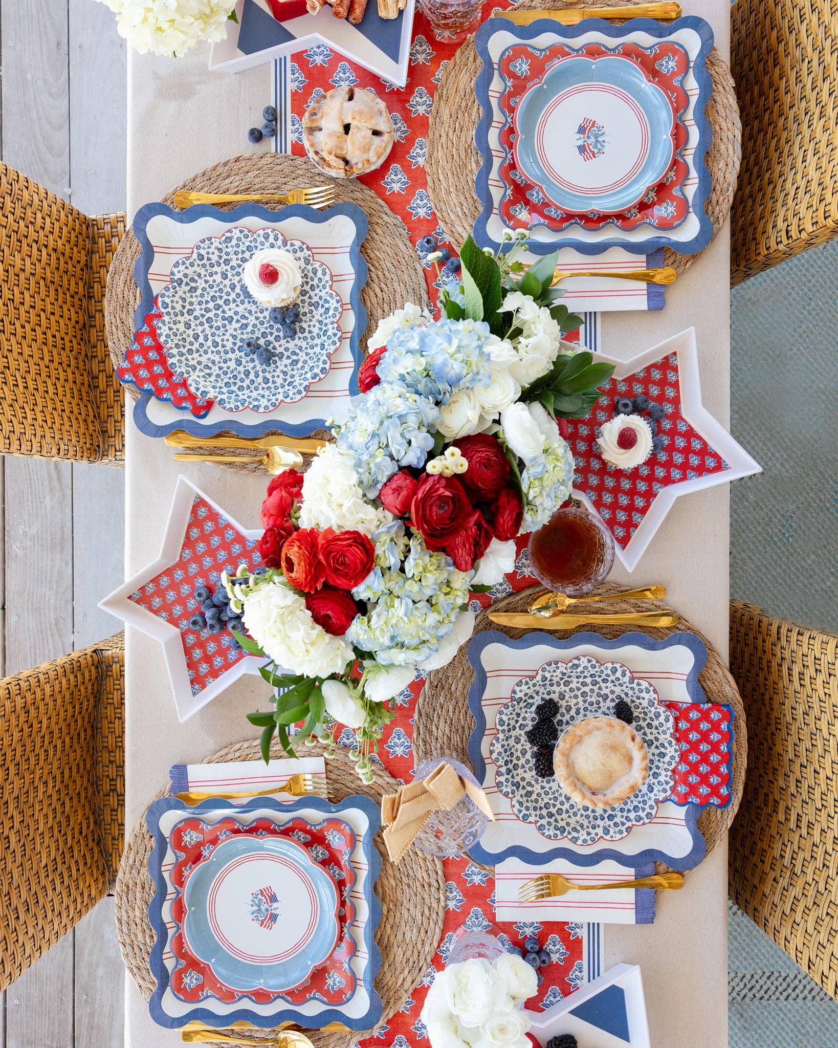 Decorative table setting with red, white, and blue plates, trays and flowers.