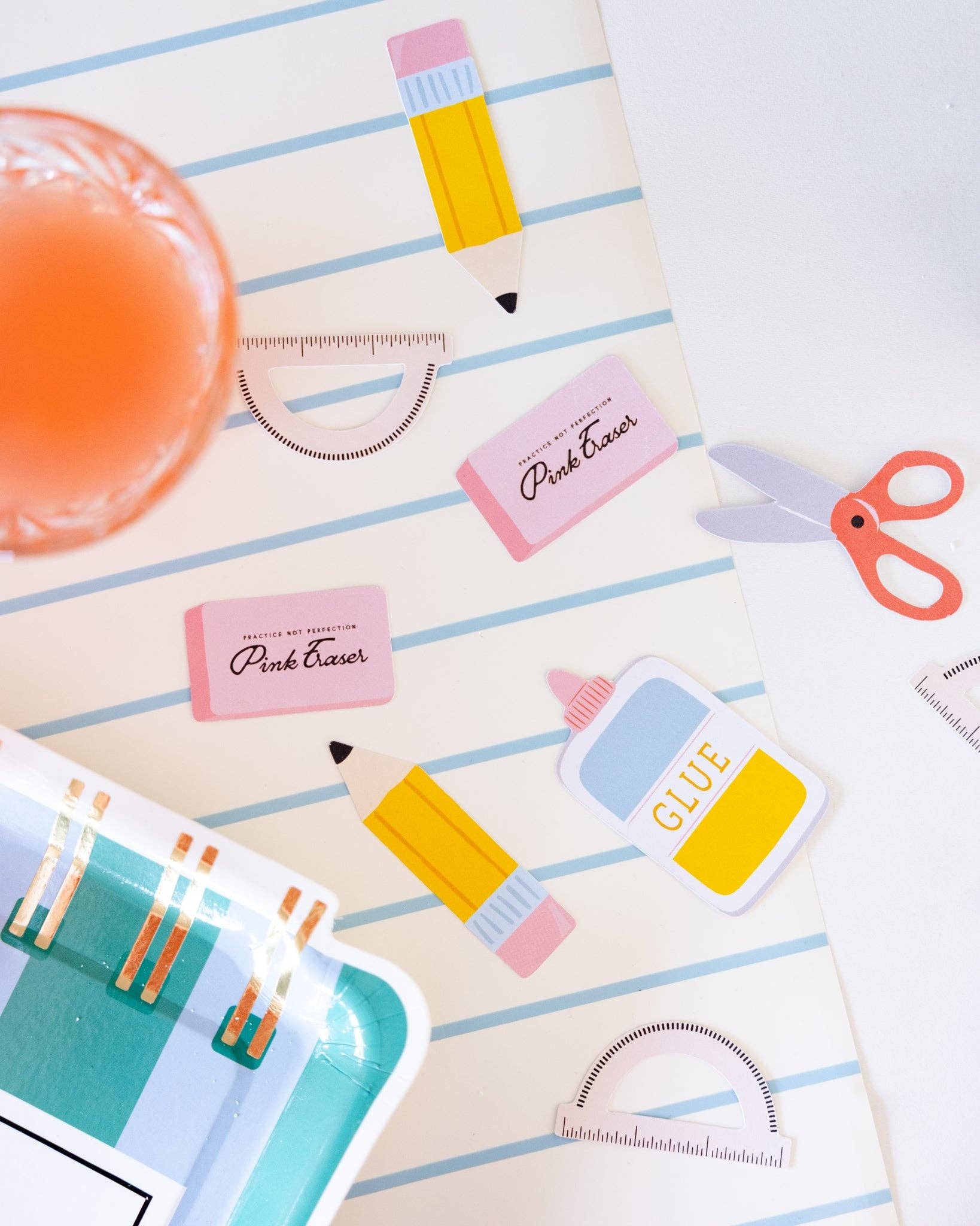 Colorful stationery items including a pencil, glue stick, and scissors on a striped background.
