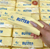 Hand holding a block of butter squishy toy with more butter packages in the background