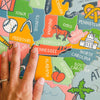 Colorful puzzle map of the United States with a hand pointing to a piece.