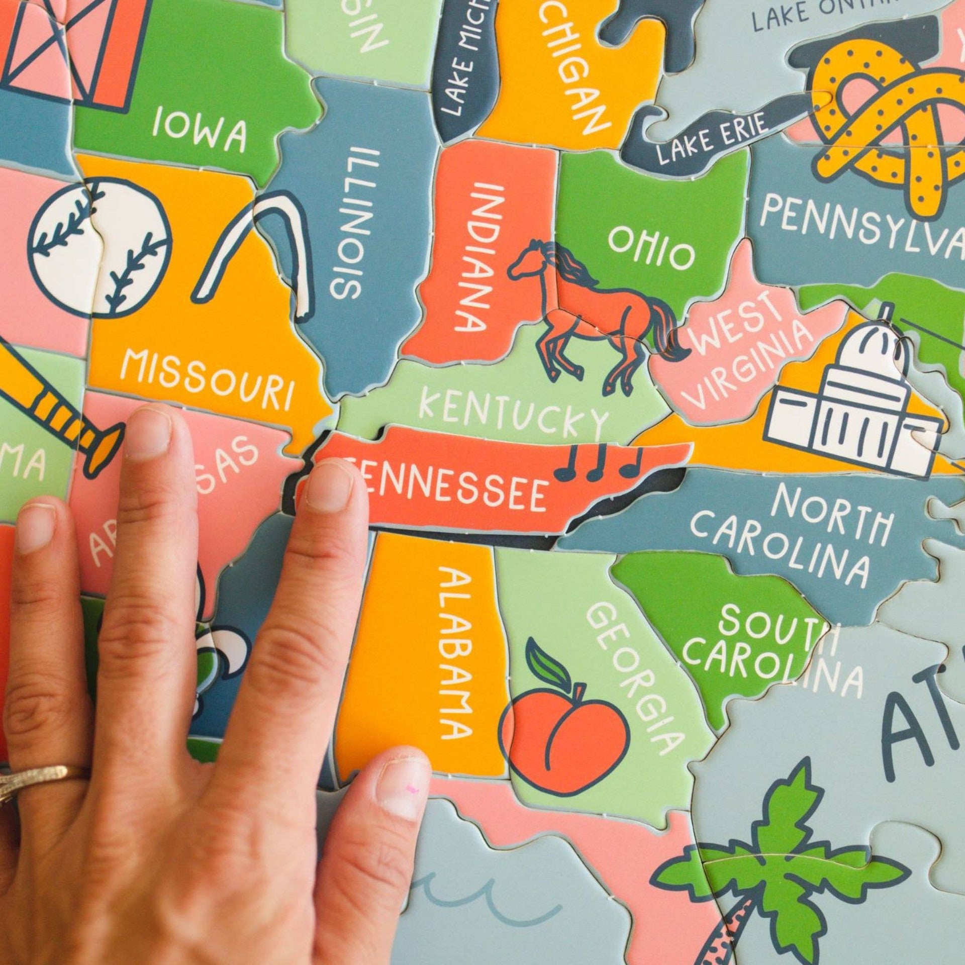 Colorful puzzle map of the United States with a hand pointing to a piece.