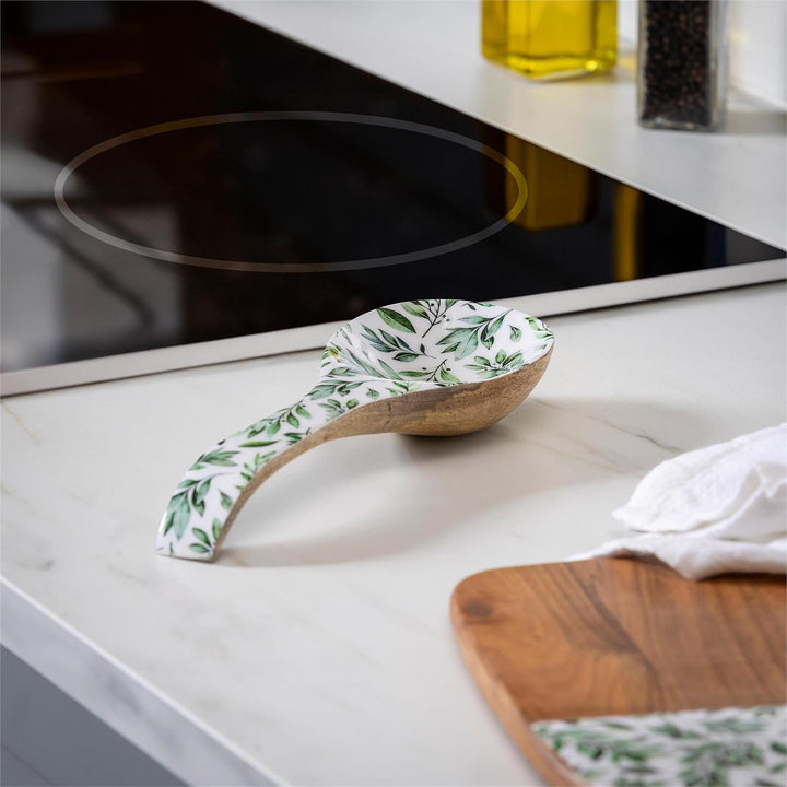 Wooden spoon with green leaf pattern on a kitchen counter
