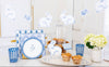 Decorative Easter setting with bunny figurines, plates, and pastries on a white surface.