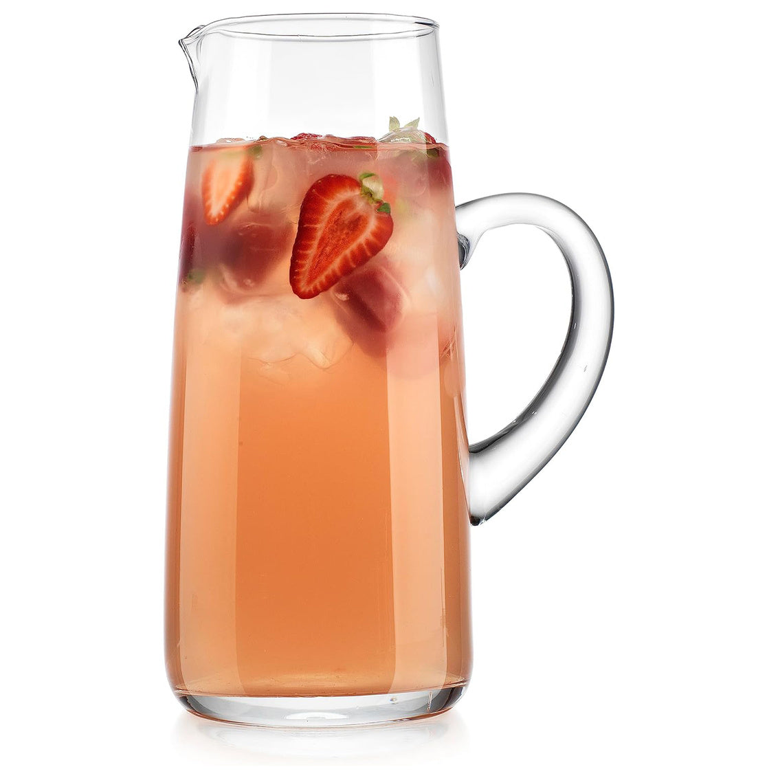 Clear glass pitcher filled with a pink beverage and sliced strawberries on a white background