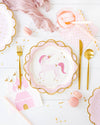 Table setting with unicorn-themed plates, pink castle napkins, and gold cutlery on a white surface.