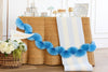 Decorative blue paper garland and blue and white striped table runner on a white and brown table with flowers and decor items.