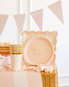 Decorative setup with 'Welcome Baby' plate, pink and gold party supplies, and bunting flags.