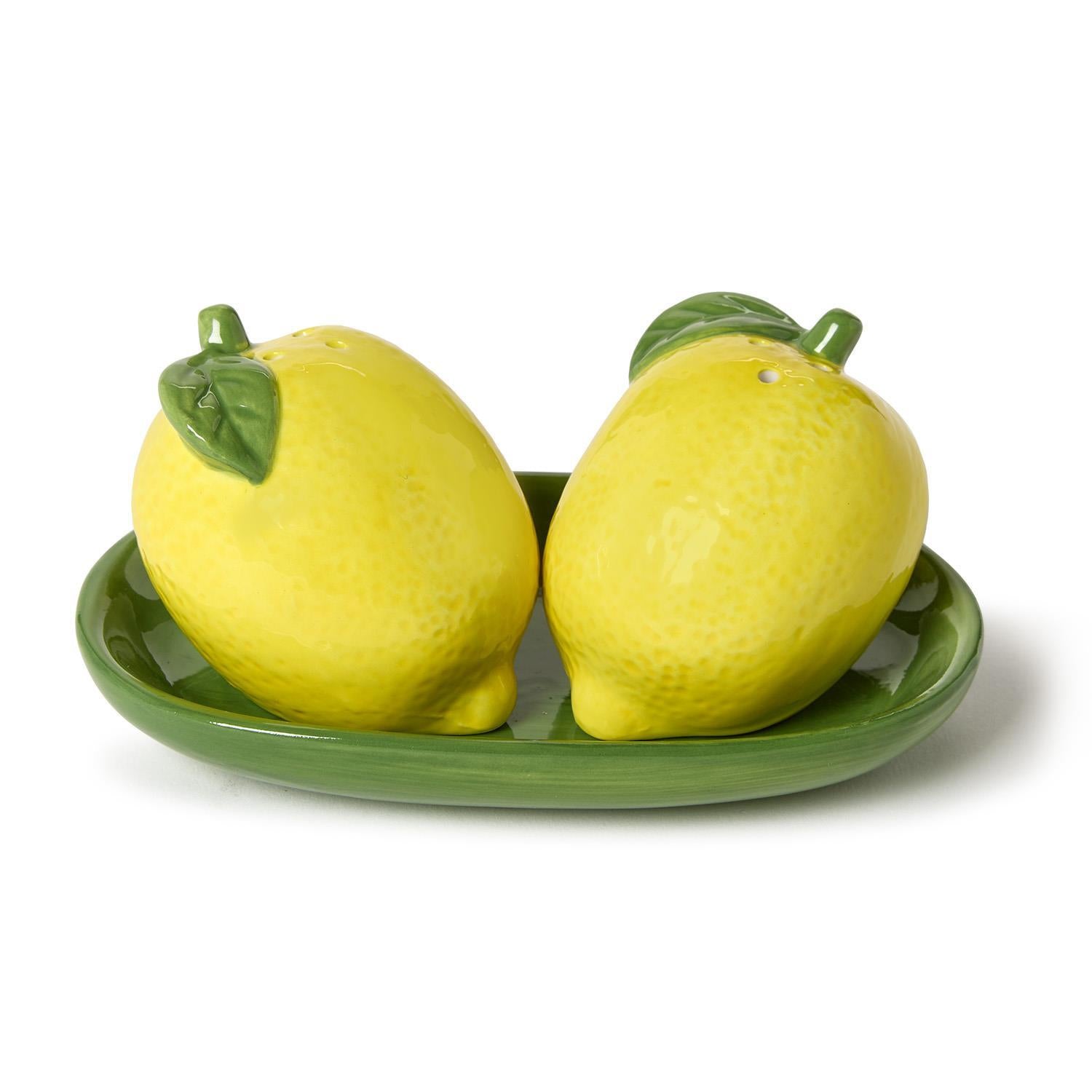 Two lemon-shaped salt and pepper shakers on a green tray with a white background