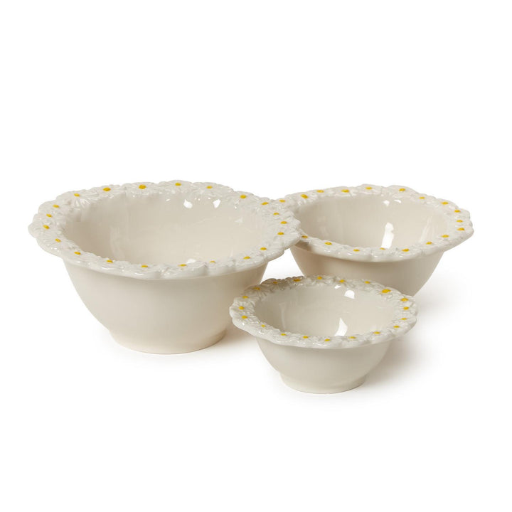 Set of three white bowls with decorative daisy patterned edge on a white background
