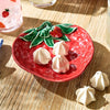 Red plate with strawberry design holding meringues on a wooden surface