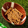 Football-shaped bowl filled with pretzel sticks on a grassy background